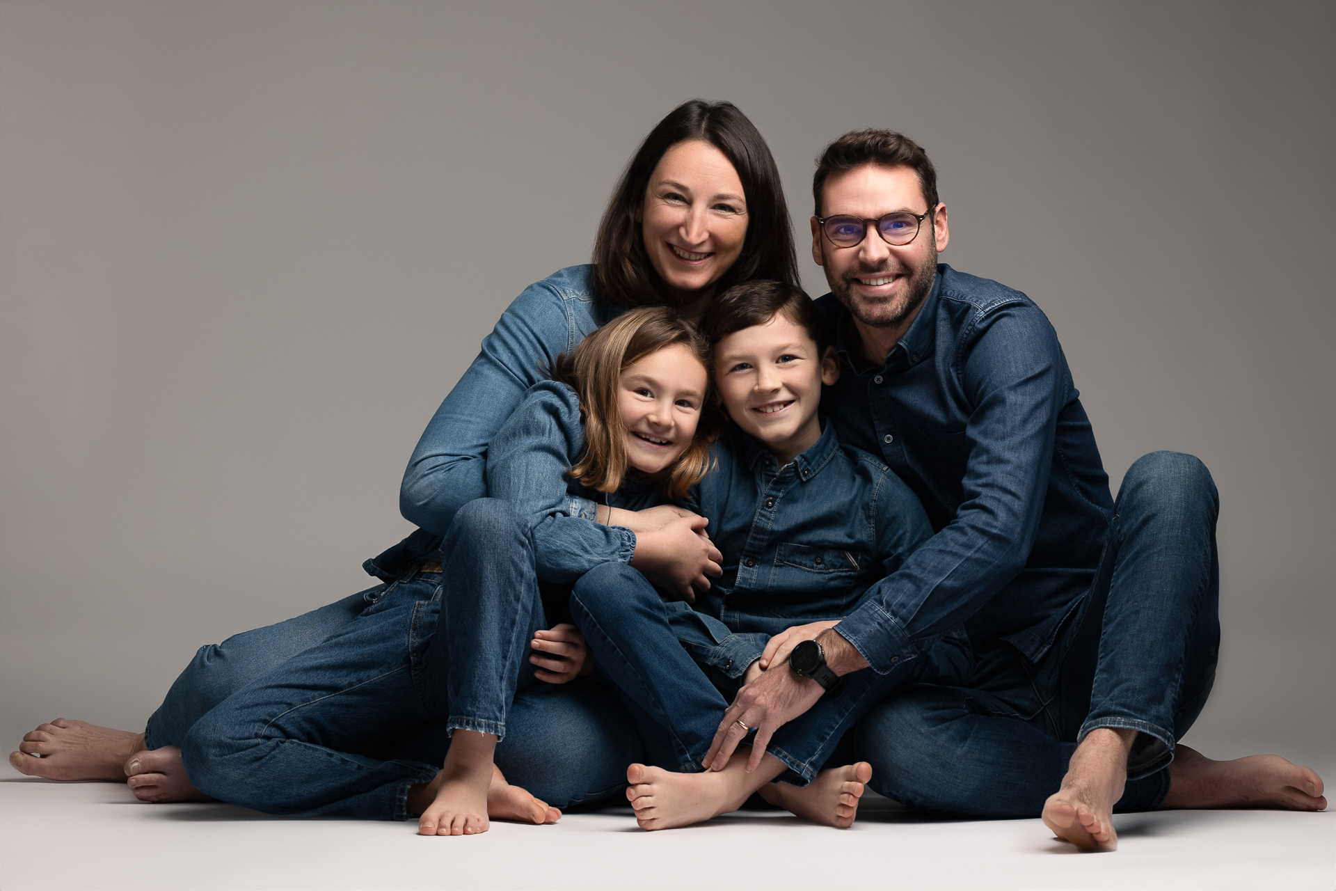 POrtrait de famille en matching outfit full jeans, entrain de faire un câlin et de rire ensemble