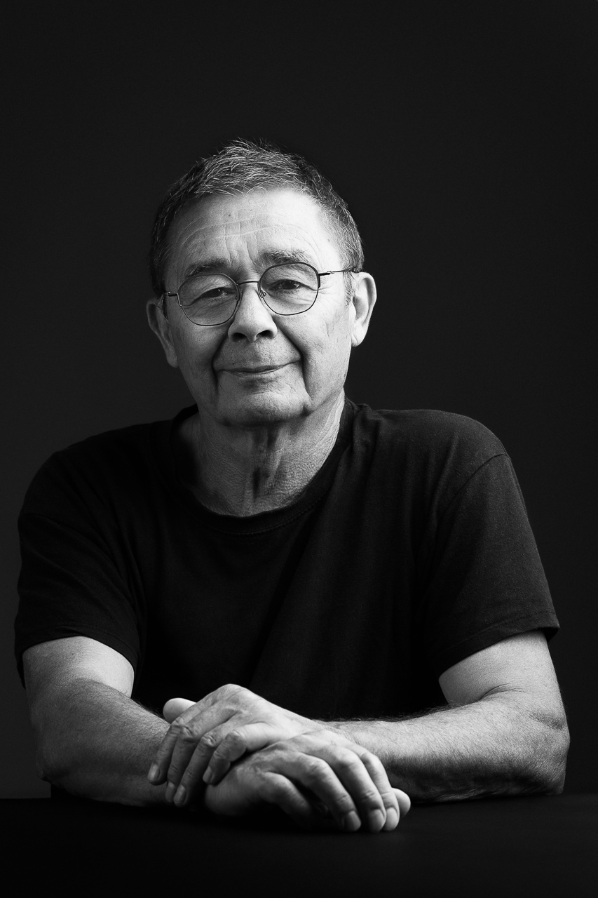 Portrait noir et blanc d’un homme senior, en t-shirt, avec expression posée, destiné à une couverture de livre, un portrait d'écrivain par Estelle de Studio Evidence, photographe professionnel à Pusignan (Rhone)