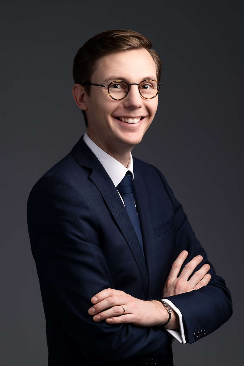 Portrait studio d’un homme en costume bleu, souriant, bras croisés, pour un usage professionnel réalisé à Pusignan (proche de Lyon) par Estelle - Studio Evidence