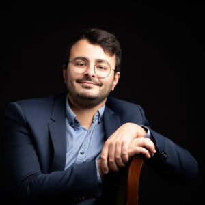 Portrait professionnel d’un homme souriant, en veste et chemise sur fond noir, studio photo à Pusignan - Studio Evidence - Estelle