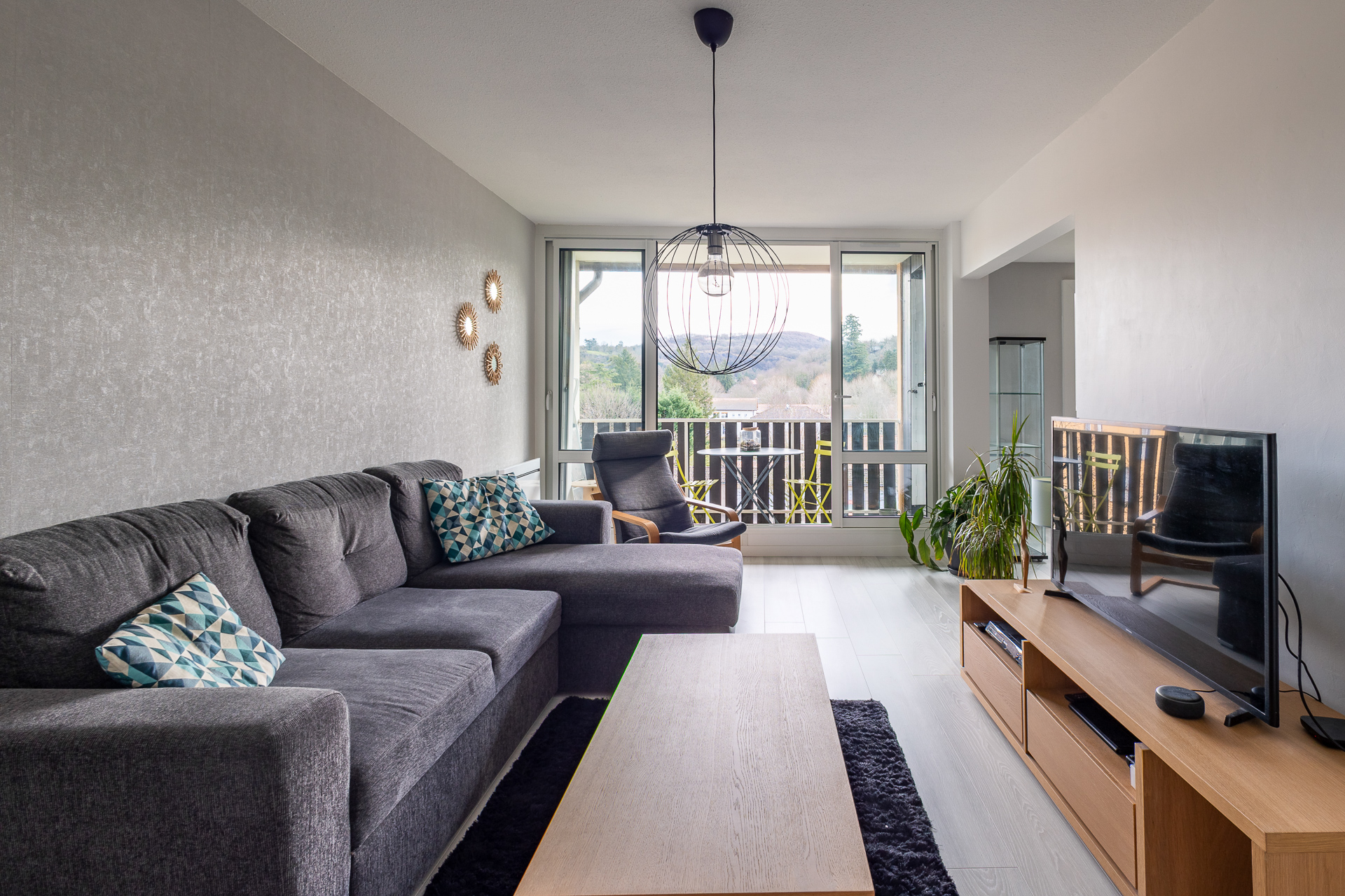 Séjour avec canapé d'angle et balcon vue dégagée sur la nature – Appartement Crémieu – Photographe immobilier Est Lyonnais