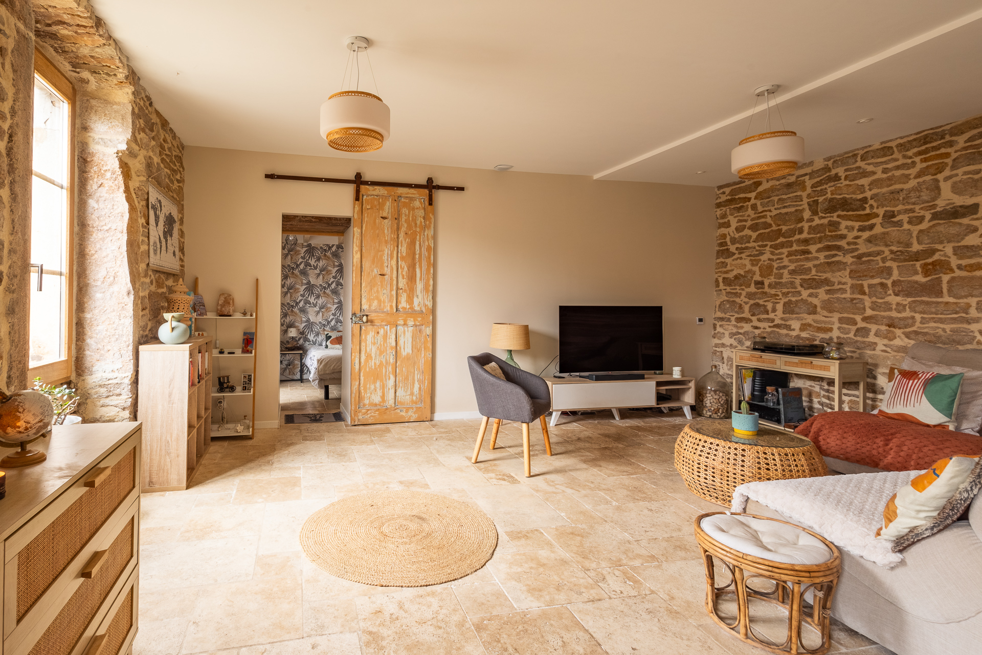 Séjour avec murs en pierre apparente et porte coulissante – Reportage immobilier Nord Isère