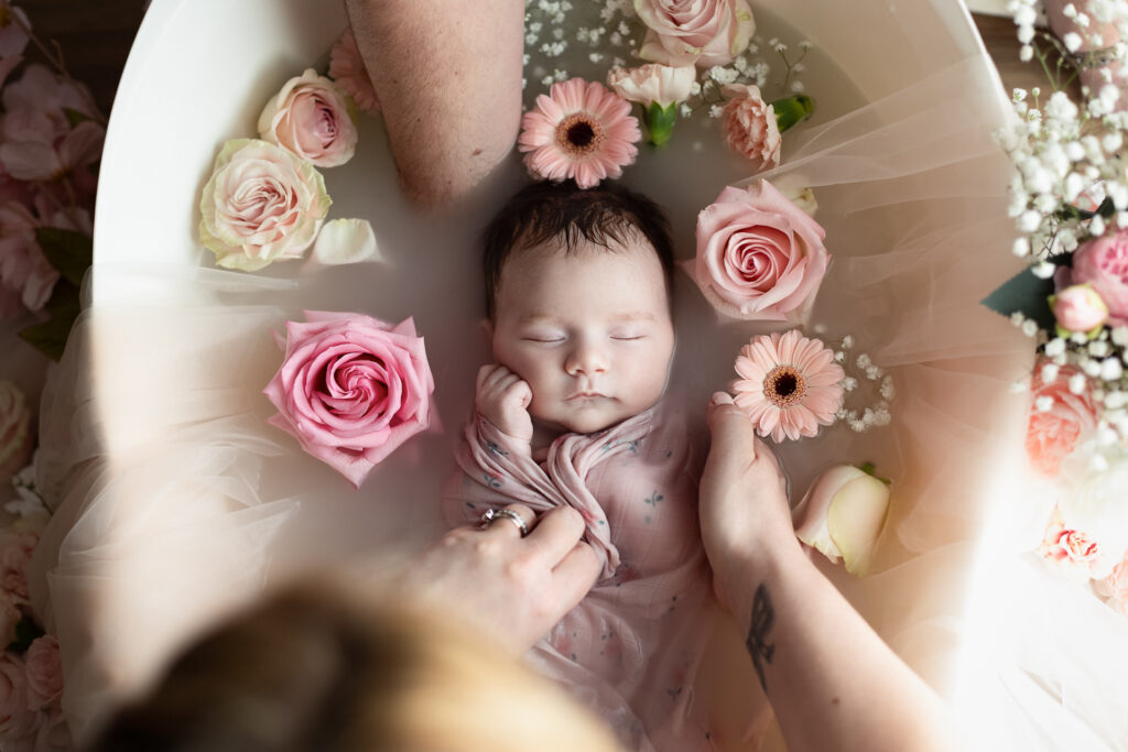 Nouveau-né endormi dans un bain fleuri de roses et gerberas roses — Studio Evidence, photographe naissance Pusignan Lyon