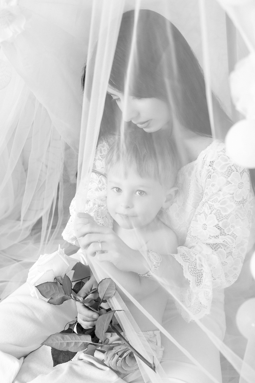 Maman et enfant blottis sous un voile de soie blanc NB — Studio Evidence Pusignan
