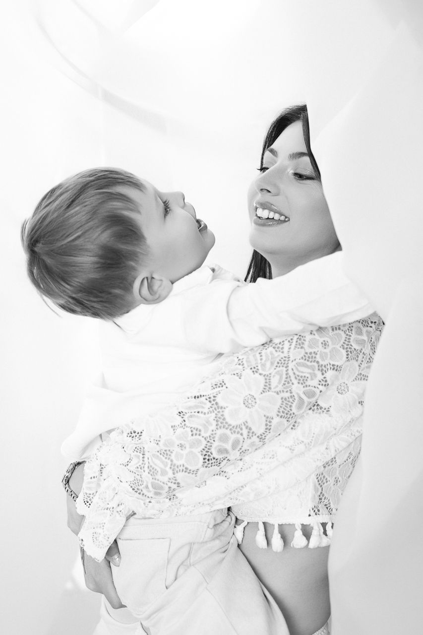 Maman portant enfant dans voilages NB — Studio Evidence Pusignan